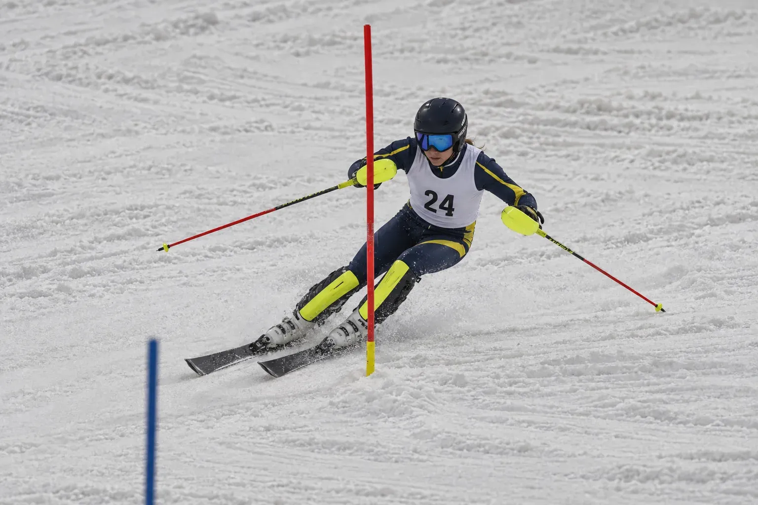 A teenager in a race suit and bib skiing through a gate in a slalom race.