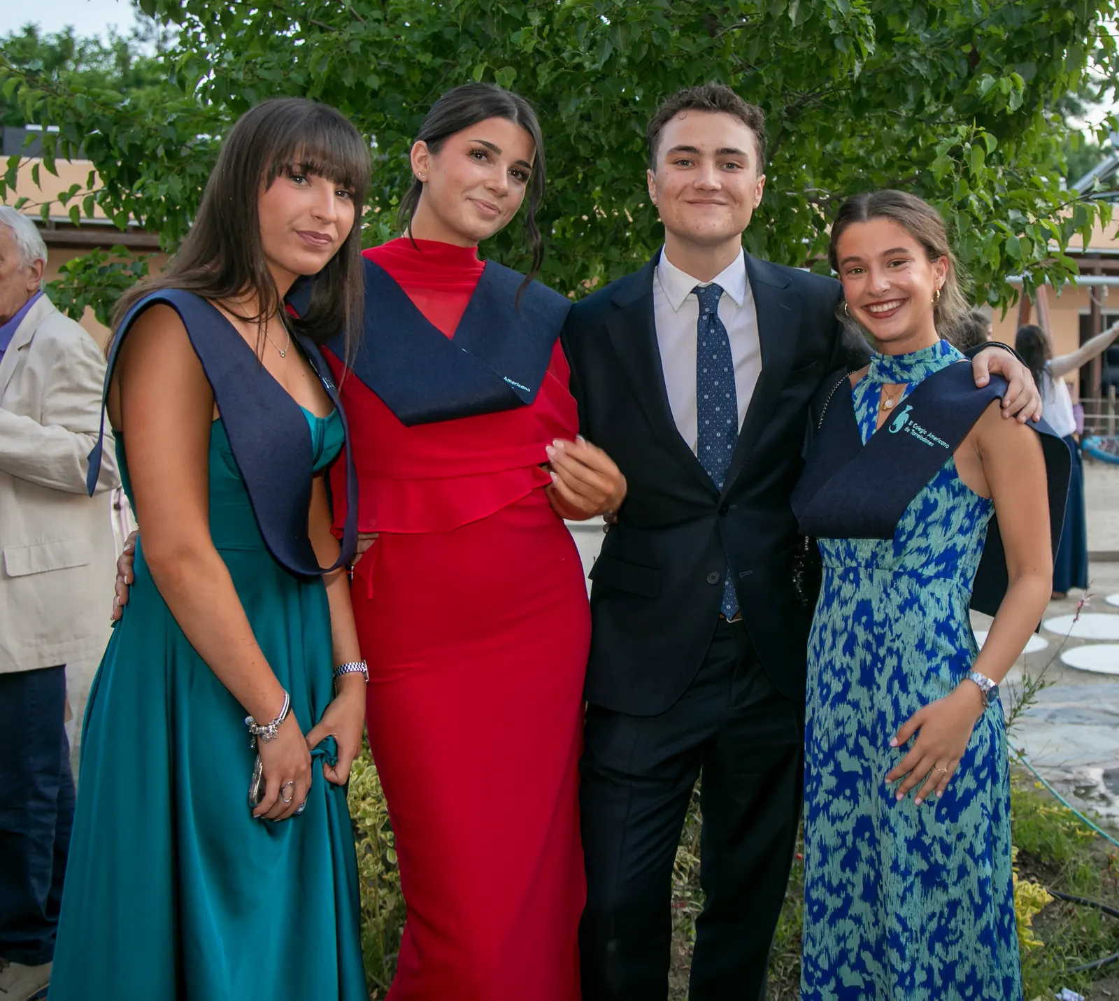Cuatro estudiantes de bachillerato, vestidos de gala, posan juntos el día de su graduación.