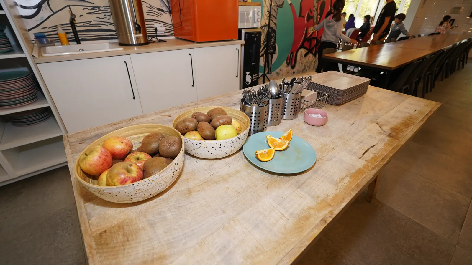 Una encimera de cocina con cuencos de manzanas, kiwis y naranjas.