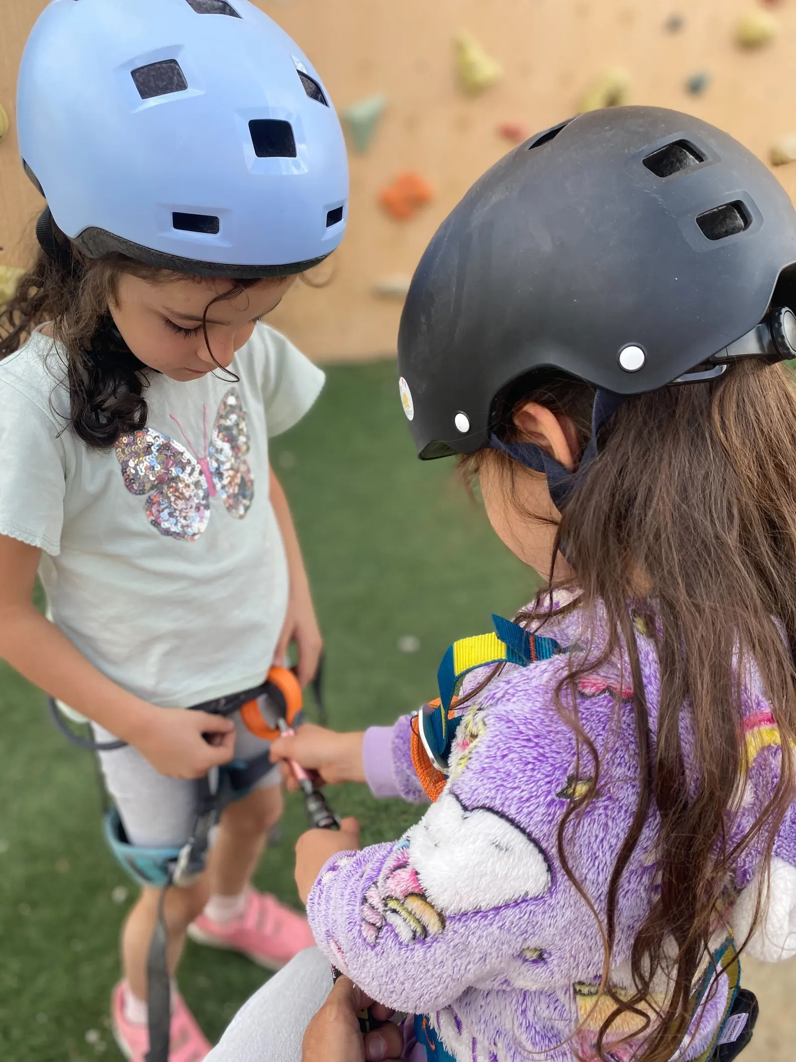 Dos niñas se ajustan el casco antes de empezar una actividad al aire libre en el campus.