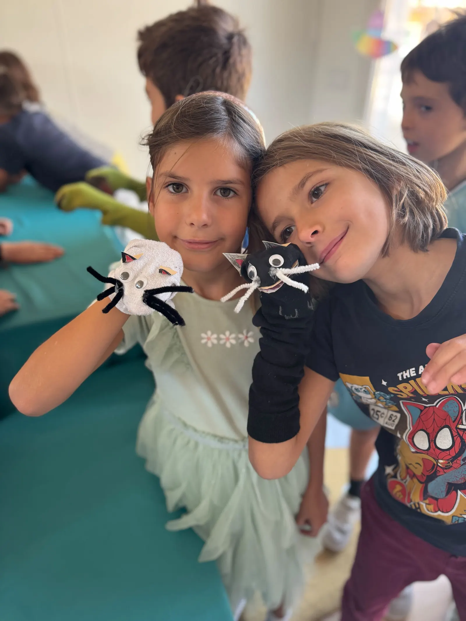 Dos niñas de primaria muestran a cámara las marionetas de dedo que acaban de hacer.