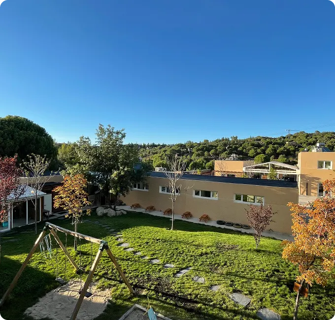 Vista del campus desde arriba: el edificio bajo, el jardín y los montes al fondo.