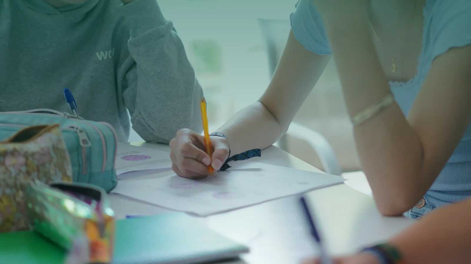 Primer plano de la mano de un alumno escribiendo con lápiz en un cuaderno.